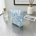 Close-up of a blue floral quilted pouch on a glass desk with home decor accessories - White with Blue Flowers