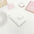 Detailed view of a white pleated mini card holder with a portable snap button closure - White