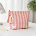 Vue détaillée d'une trousse de maquillage rayée en PVC avec détail de glands - Rayures Fines Rose Et Beige