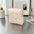 Macro view of a quilted pink cosmetic bag with sweet bow patterns on a glass surface - Striped Bow