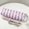 Borsa da viaggio a righe viola con arricciacapelli rosa coordinato su tavolo. - Strisce Bianche e Viola