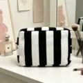 Primer plano de un neceser de pana con rayas blancas y negras sobre un tocador elegante - Rayas Blancas y Negras