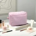 Vue détaillée d'une trousse à maquillage en seersucker à carreaux roses et cosmétiques - Rose