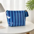 Blaue gestreifte PVC Kosmetiktasche wasserdicht mit Quaste auf einem weißen Tisch - Dünne Königsblaue Streifen