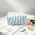 Blue and white striped quilted cosmetic bag with pink zipper in a lifestyle setup - Blue Stripe