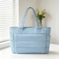 Vue détaillée d'un sac cabas matelassé bleu clair sur une table blanche dans une pièce - Bleu