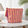 Détail d'une trousse de maquillage rayée en PVC imperméable avec des glands colorés - Fines Rayures Orange et Rouge