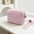 Detalle de un neceser rosa con textura de gofre y cremallera sobre mesa blanca - Rosa