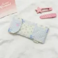 Primer plano del estampado floral acolchado y el botón de presión de corazón en este estuche - Azul y Blanco