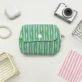 Close-up detail of a green tweed flap coin purse with colorful stripes and a white button. - Green