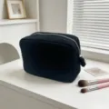 Neceser negro grande con textura de gofre y brochas de maquillaje en sala luminosa - Negro