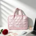 Close-up of pink laptop bag showing heart-shaped quilting and smooth satin texture - Pink
