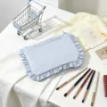 Macro view of blue seersucker striped cosmetic bag with elegant ruffled edges - Blue