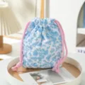 Close-up of a quilted floral drawstring pouch featuring pink cords and blue flower pattern - White with Blue Flowers