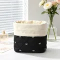 Close-up of a quilted black cosmetic bag with white bow patterns and drawstring closure - Black