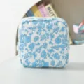 Detail van het ribfluwelen tasje met blauwe bloemen, close-up van de zachte stof textuur. - Wit met blauwe bloemen
