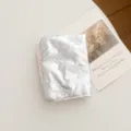 Detalle de funda para pasaporte plateada y acolchada con bordado elegante de lazos. - Lazo / Plateado