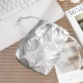 Detalle de neceser de PU plateado metalizado con lazos grabados y cierre de cordón. - Patrón de Lazo / Plateado