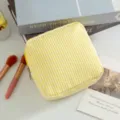 Detalle de un neceser de seersucker a rayas amarillas y blancas sobre un escritorio - Amarillo