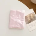Primer plano de la suave textura de satén acolchado rosa y el diseño de lazo del porta pasaporte - Lazo / Rosa