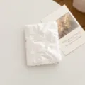 Vista detallada del portapasaporte acolchado blanco con un diseño elegante de moño - Lazo / Beige