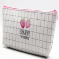 Makro-Detail einer weißen Gitter-Ledertasche mit süßem Erdbeerdruck und Reißverschluss - Zwei Erdbeeren Stil