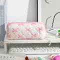 Close-up of pink quilted pencil case with bow pattern on a clean white desk setup - Large Capacity / Pink Bow on White Background