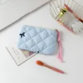 Neceser acolchado azul con cordón rosa y bordado de lazo sobre un escritorio blanco - Tela Azul con Lazo Bordado