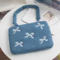 Detailansicht einer blauen Denim-Laptoptasche mit weißen Schleifen auf dem Tisch - 13 Zoll / Denim Schmetterling