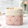 Detailed macro shot of a pink quilted cotton cosmetic bag with cute bow embroidery patterns - Pink