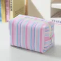 Detailed close-up of the striped seersucker makeup bag showing soft texture and zipper. - Blue-Pink Striped