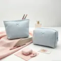 Primer plano de neceseres azules con textura de gofre y lazos en escena de tocador - Bolso de mano / 20x18x5.5cm / Azul