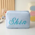 Vue détaillée de la trousse de maquillage rayée avec broderie Skin bleue - Style Brodé Skin / Bleu