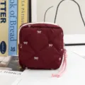 Detailed view of the elegant maroon quilted cosmetic pouch with white embroidered bows - Angola Red