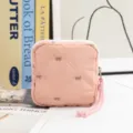 Macro view of pink quilted cosmetic pouch featuring delicate embroidered bow patterns - Pink