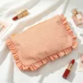 Detailed view of the orange striped bubble gauze makeup bag with ruffle trim. - Orange