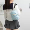 Vista trasera de mochila acolchada a cuadros azules con bordado de lazo rosa en modelo - Cuadros Azules con Lazo