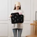 Detailed view of black tablet sleeve held by model in a minimalist setting - Black / 11"