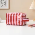 Primer plano de un neceser de rayas rojas y rosas brillantes en un escritorio - Rayas Finas Rojas y Rosas