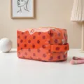 Bolsa de cosméticos con lunares naranjas de gran capacidad en un entorno minimalista - Lunares Naranja Rojo