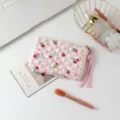 Neceser acolchado con estampado floral en un escritorio con accesorios de belleza - Flores Pequeñas Rojas