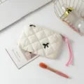 Primer plano de estuche acolchado blanco con lazo bordado y asa de cuerda rosa - Tela Beige con Lazo Bordado