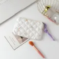 Detalle de un neceser de maquillaje acolchado blanco con tirador de cuerda morada. - Floral Blanco