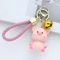 Close-up view of pink resin pig keychain with knitted texture and golden bell charm - Pink Pig / Pink Pig