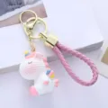 Close-up detail of a cute white resin unicorn keychain with a pink braided wrist strap. - Single Piece / Pink Unicorn