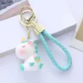 Close-up of cute resin unicorn keychain with blue woven strap and gold metal hardware - Single Piece / Green Unicorn