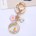 Close-up of cute rabbit and cherry blossom charms on a gold-tone alloy keychain. - Floral Bunny
