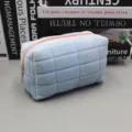 Weiche gesteppte hellblaue Kosmetiktasche mit Pfirsich-Reißverschluss auf einem Schreibtisch. - Einfaches Kissen-Design (Einfaches Federmäppchen) / Blau