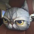 Detailed macro view of a 3D grumpy cat car headrest pillow on a brown leather seat - Fierce Cat