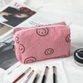 Vista detallada del neceser de pana rosa con patrones bordados de caritas sonrientes negras - Rosa / 16*7*9cm